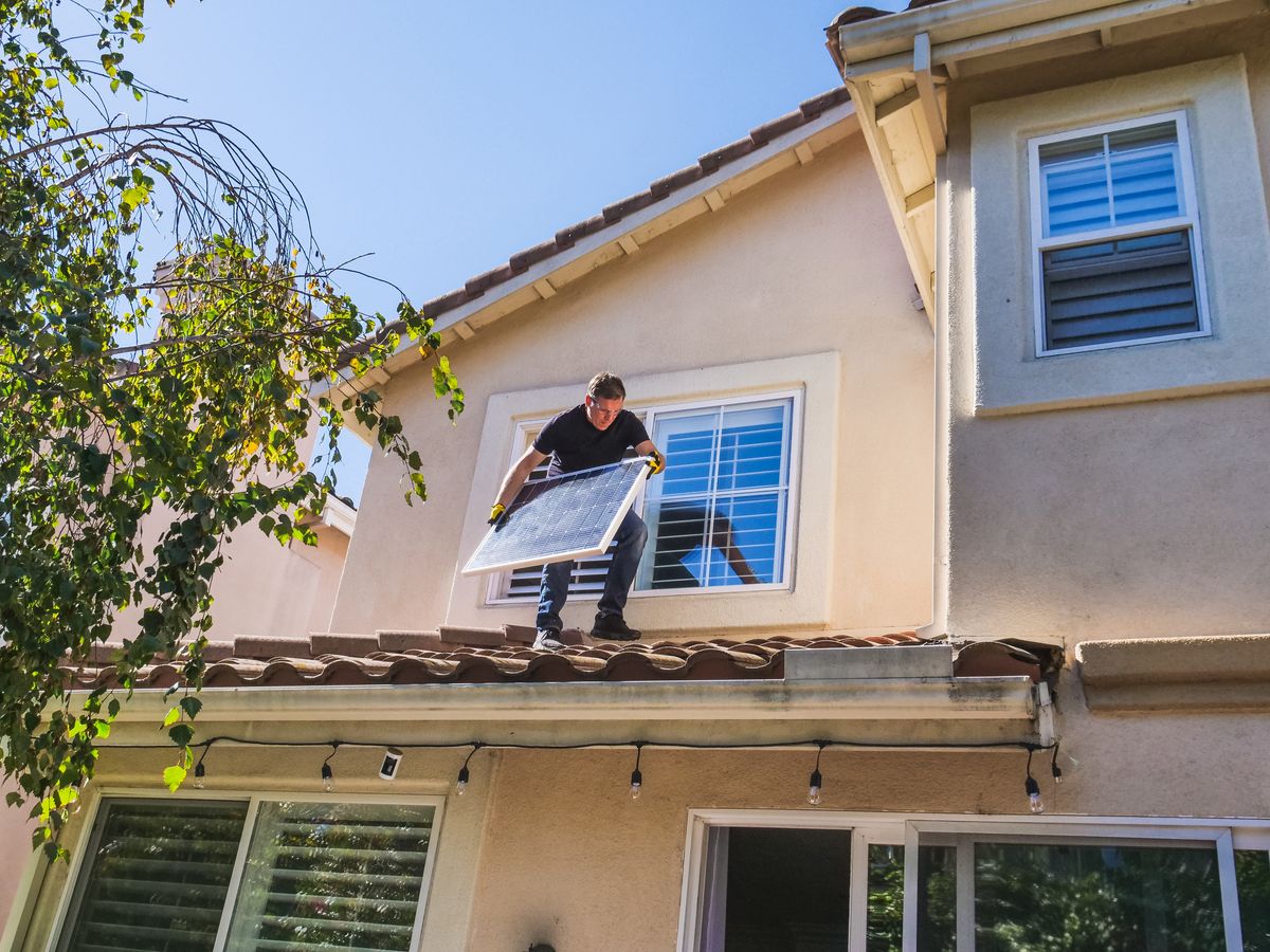 Close view of an installer seating a solar panel on a residential roof